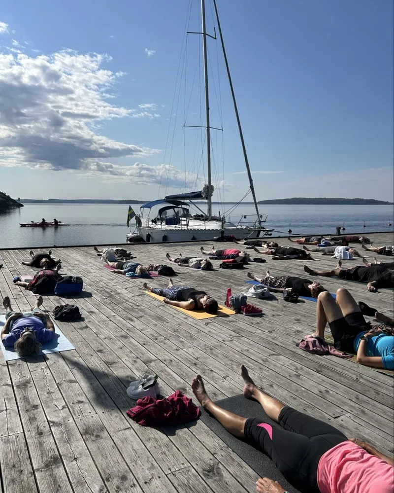 Sommaryoga på bryggan vid vattnet en solig morgon