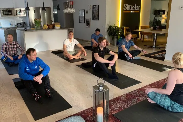 Medarbetare sitter på yogamattor i Structor Östergötlands kontor