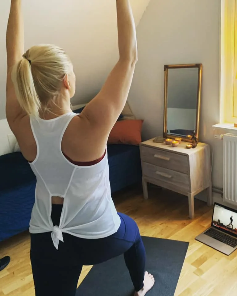 Yoga hemma i vardagsrummet med en yogafilm på datorn